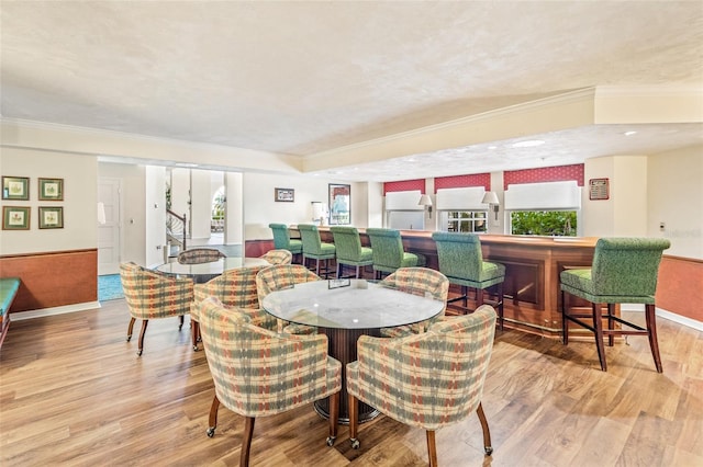 dining space featuring plenty of natural light, wood finished floors, and crown molding