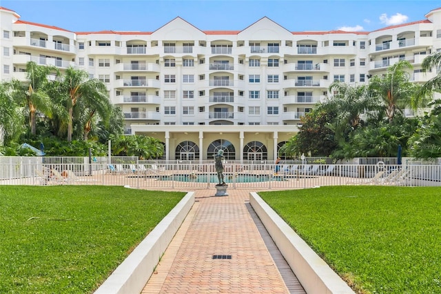 view of property's community with a yard, fence, and a pool