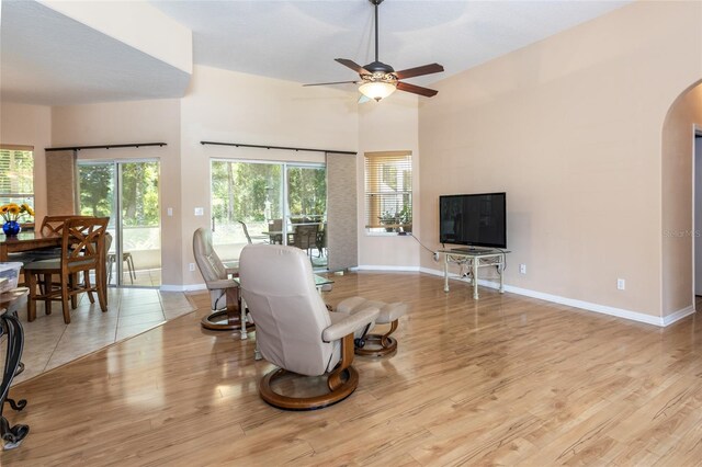 living room with a high ceiling, light hardwood / wood-style flooring, and ceiling fan