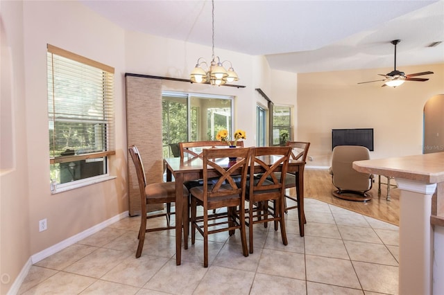 dining area featuring baseboards, ceiling fan with notable chandelier, light tile patterned flooring, and a healthy amount of sunlight