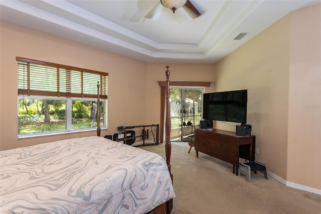 bedroom featuring light colored carpet, a tray ceiling, visible vents, and baseboards