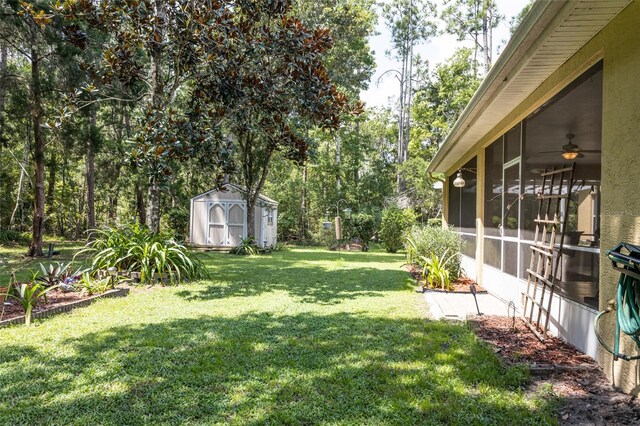 view of yard featuring ceiling fan, a sunroom, and a storage shed