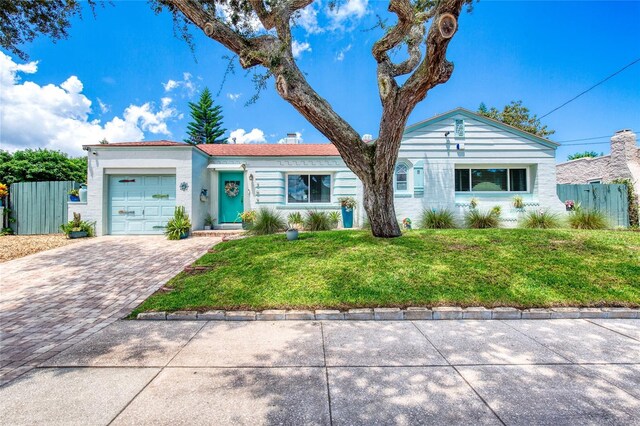 ranch-style home with a garage and a front lawn