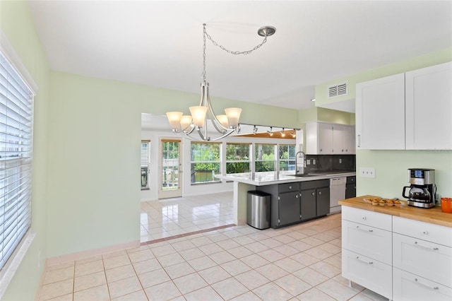 kitchen featuring white cabinets, decorative light fixtures, dishwashing machine, and sink