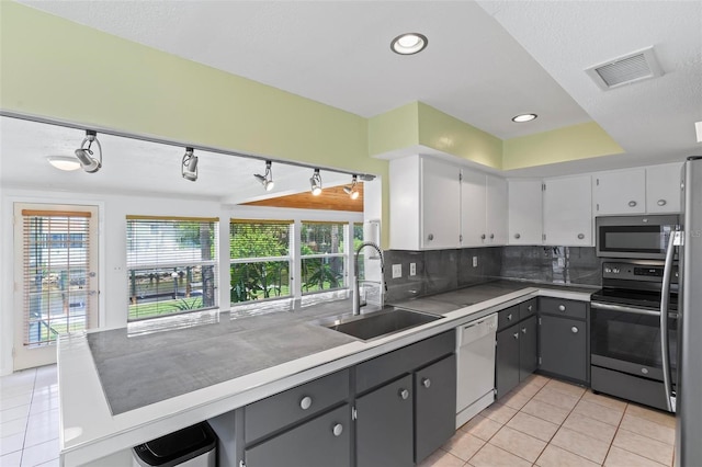 kitchen with sink, gray cabinets, light tile patterned floors, appliances with stainless steel finishes, and tasteful backsplash