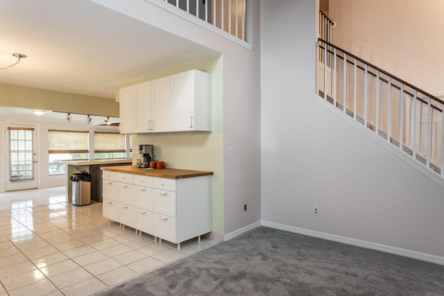 kitchen with white cabinetry, light colored carpet, and wood counters