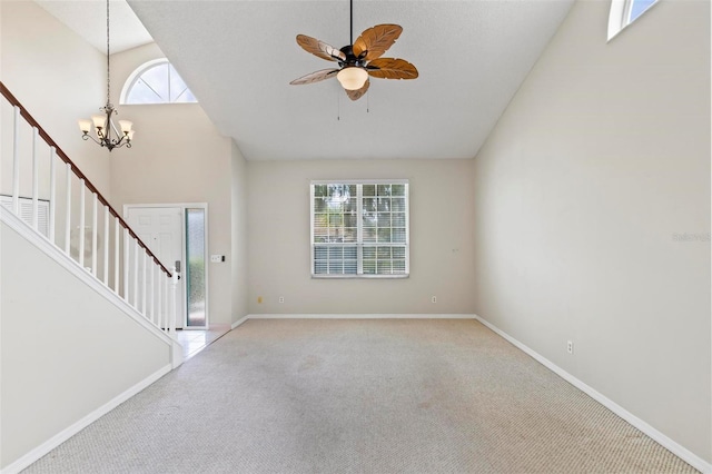 unfurnished living room with ceiling fan with notable chandelier, light carpet, and high vaulted ceiling