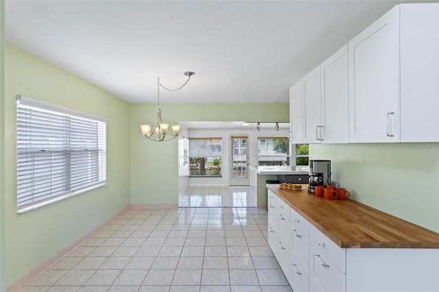 kitchen with a healthy amount of sunlight, pendant lighting, white cabinetry, and butcher block counters