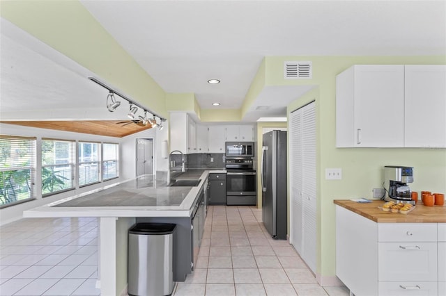 kitchen with white cabinetry, sink, a kitchen bar, light tile patterned floors, and appliances with stainless steel finishes