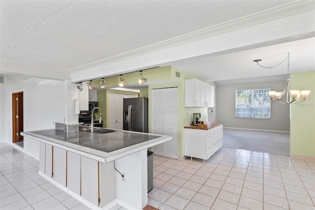 kitchen with white cabinetry, stainless steel appliances, an inviting chandelier, a textured ceiling, and light tile patterned flooring