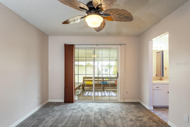 empty room with ceiling fan, sink, light colored carpet, and a textured ceiling