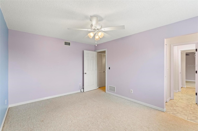 unfurnished room with light carpet, a textured ceiling, and ceiling fan