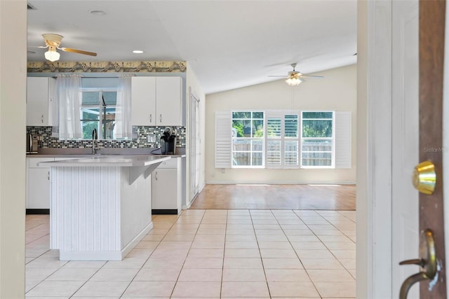 kitchen with ceiling fan, backsplash, light tile patterned flooring, and lofted ceiling