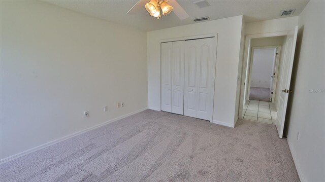 unfurnished bedroom featuring a closet, ceiling fan, and light colored carpet