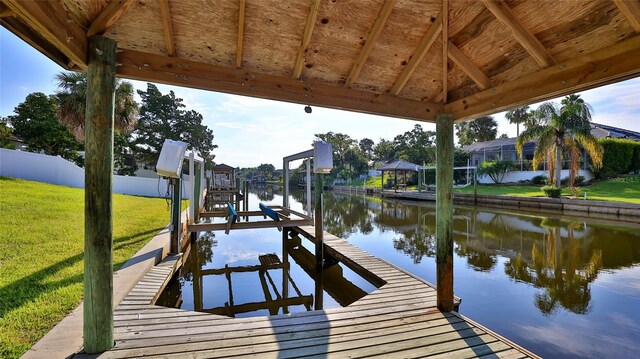 dock area with a gazebo, a water view, and a yard