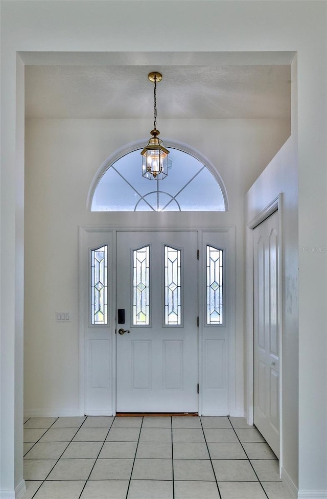 entrance foyer featuring a chandelier, light tile patterned floors, and plenty of natural light