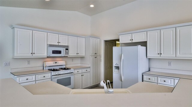 kitchen with white cabinetry, white appliances, sink, and vaulted ceiling