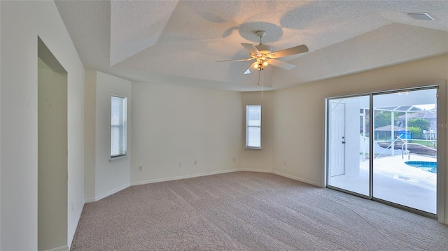 spare room with a raised ceiling, ceiling fan, light carpet, and a textured ceiling