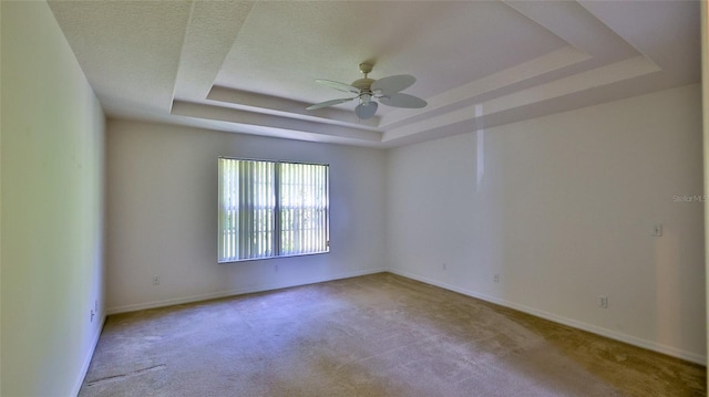 carpeted spare room featuring ceiling fan, a raised ceiling, and a textured ceiling