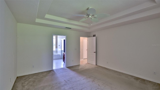 unfurnished room featuring light colored carpet, a raised ceiling, and ceiling fan