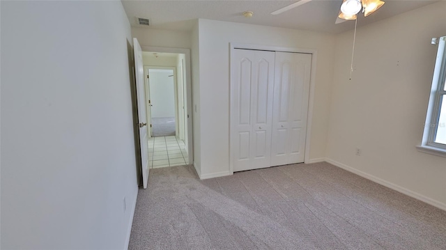 unfurnished bedroom with ceiling fan, a closet, and light carpet