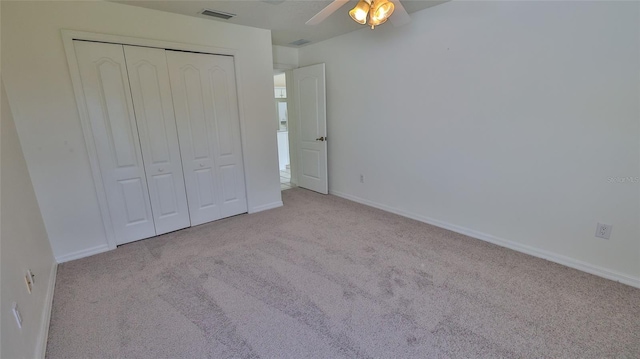 unfurnished bedroom with ceiling fan, light carpet, and a closet