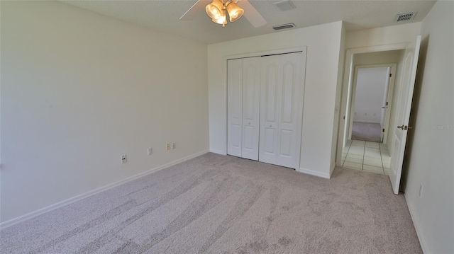 unfurnished bedroom with light carpet, a closet, and ceiling fan