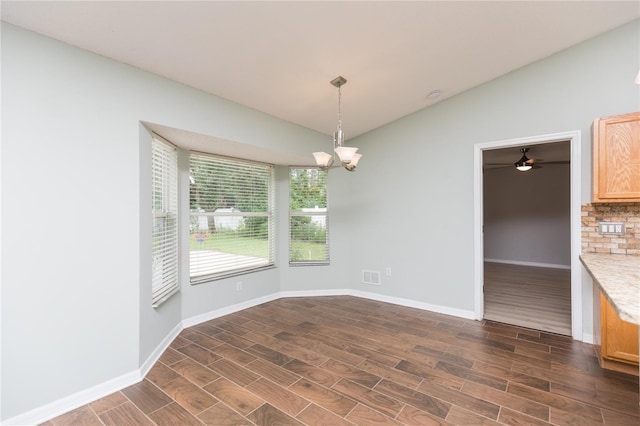 unfurnished dining area featuring lofted ceiling, a notable chandelier, dark wood finished floors, and baseboards