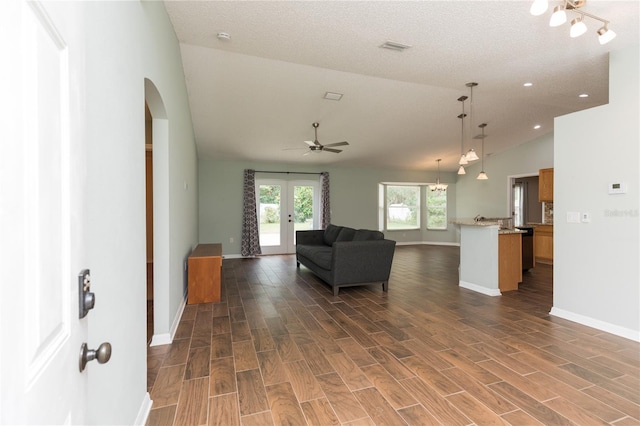 unfurnished living room with dark wood-style flooring, visible vents, baseboards, vaulted ceiling, and french doors