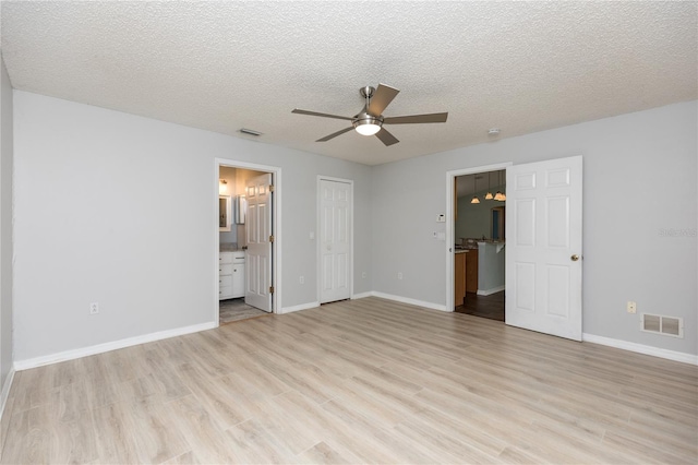 unfurnished bedroom with visible vents, light wood-style flooring, and baseboards