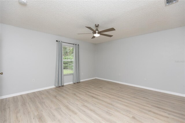 unfurnished room featuring a textured ceiling, visible vents, baseboards, a ceiling fan, and light wood finished floors