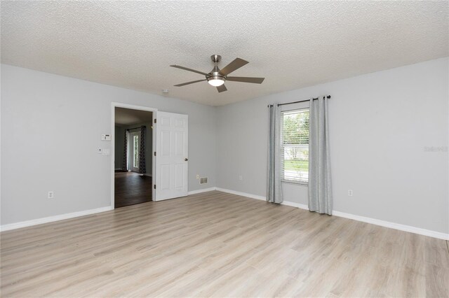 empty room featuring light wood-style flooring, baseboards, and a textured ceiling