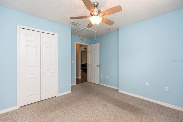 unfurnished bedroom featuring a textured ceiling, visible vents, and light colored carpet