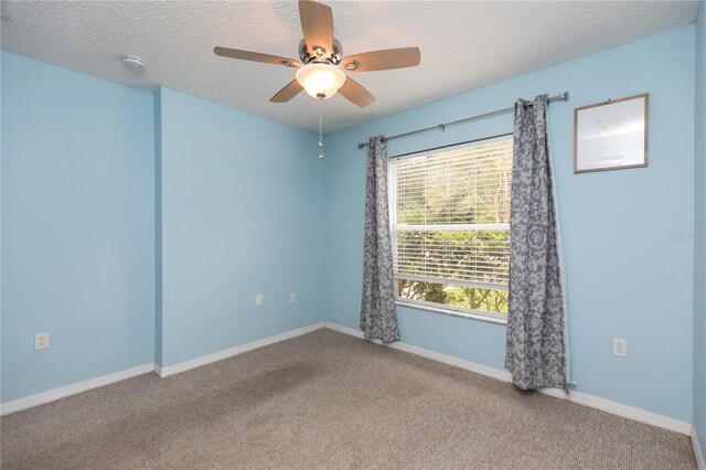 empty room featuring ceiling fan, baseboards, a textured ceiling, and carpet flooring