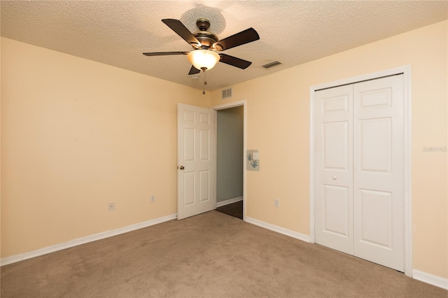 unfurnished bedroom featuring a textured ceiling, a closet, visible vents, and light colored carpet