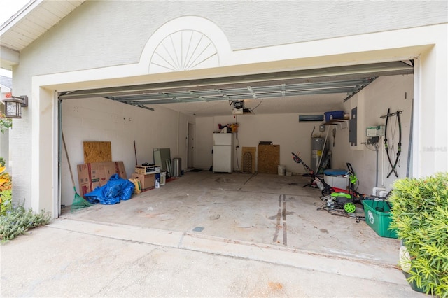 garage featuring a garage door opener, freestanding refrigerator, electric water heater, and driveway