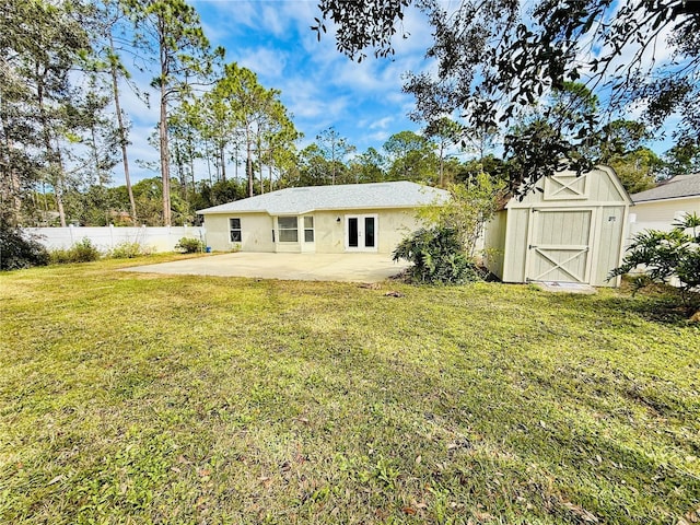 rear view of property featuring a lawn, a storage shed, a patio area, fence, and an outdoor structure