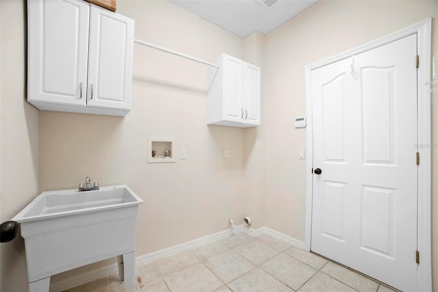 laundry room with hookup for a washing machine, light tile patterned floors, cabinets, and sink