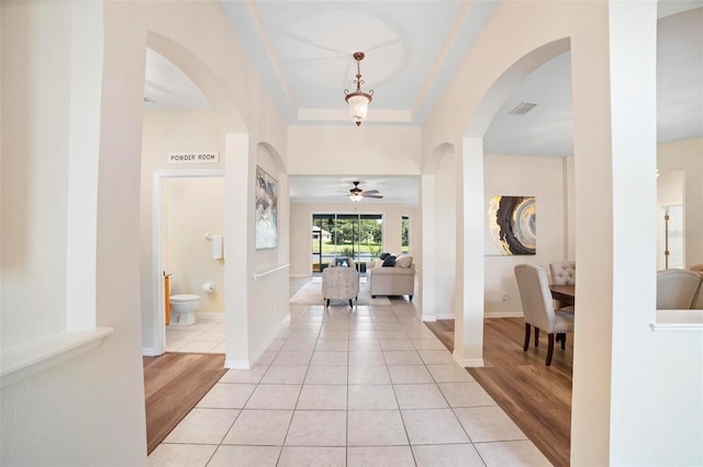 foyer entrance featuring ceiling fan, light tile patterned flooring, and a raised ceiling