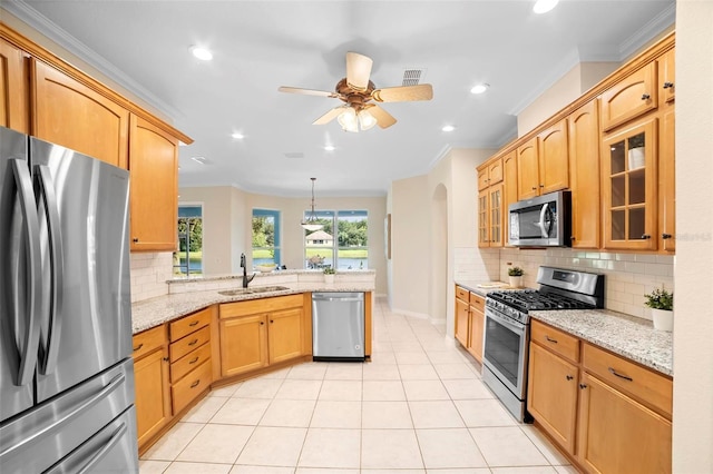 kitchen with sink, hanging light fixtures, light stone counters, crown molding, and appliances with stainless steel finishes