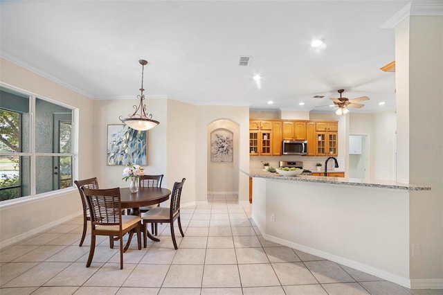 kitchen with light stone countertops, crown molding, light tile patterned flooring, and stainless steel appliances