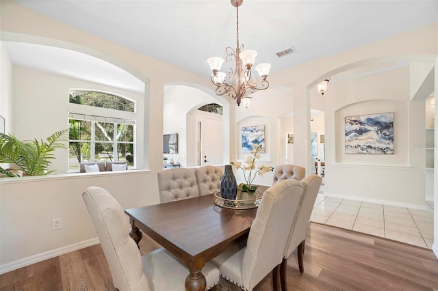 dining space with wood-type flooring and a notable chandelier