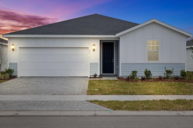 single story home featuring a garage and a lawn