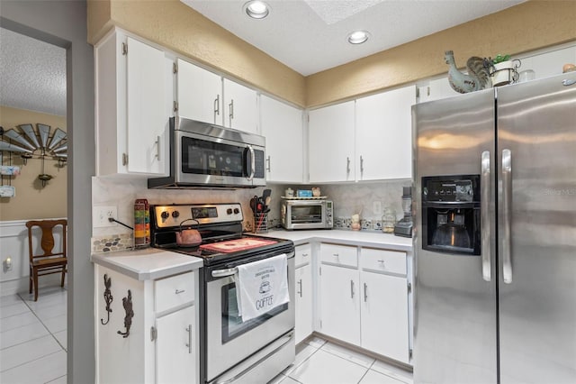 kitchen featuring white cabinetry, backsplash, appliances with stainless steel finishes, and light tile patterned floors