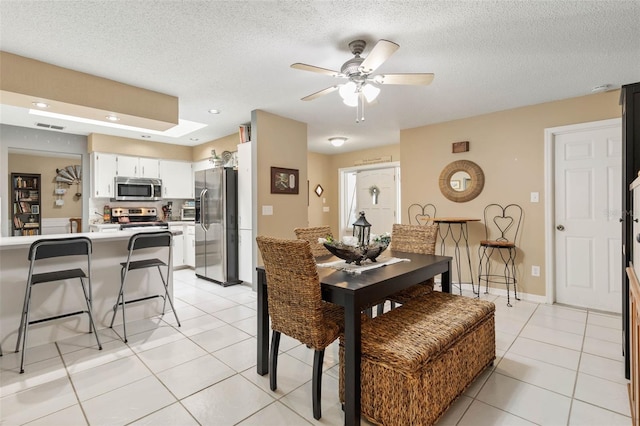 dining area with a textured ceiling, ceiling fan, and light tile patterned floors