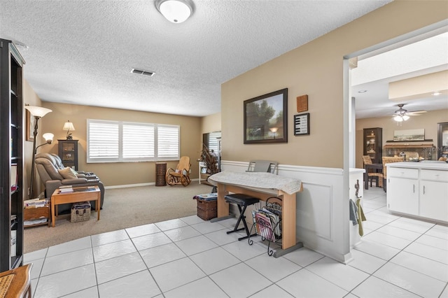 dining space with ceiling fan, light carpet, and a textured ceiling