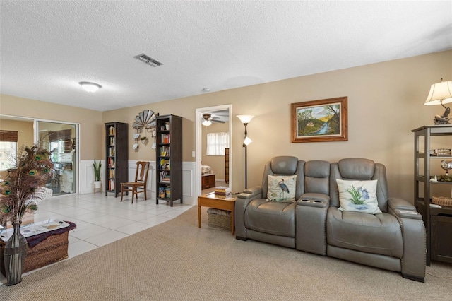 carpeted living room with a textured ceiling, ceiling fan, and a healthy amount of sunlight