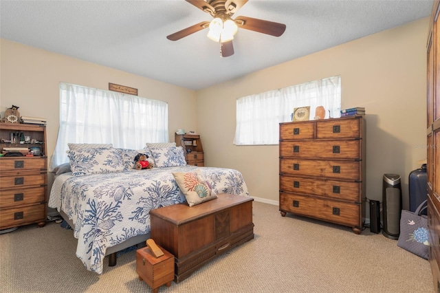 bedroom with light colored carpet, a textured ceiling, multiple windows, and ceiling fan