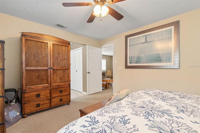 bedroom with a textured ceiling, a closet, ceiling fan, and light carpet