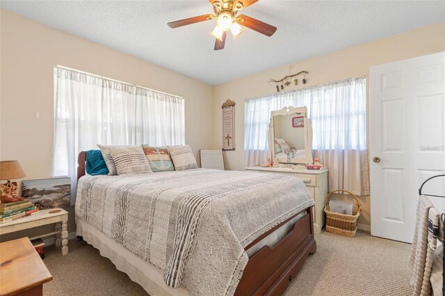 carpeted bedroom with ceiling fan and a textured ceiling